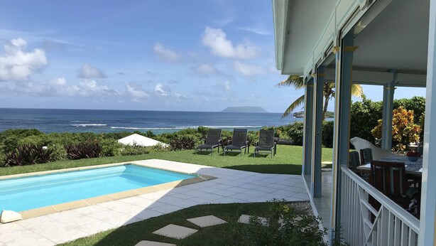 Ein Pool mit Meerblick, Sitzgelegenheiten im Freien und eine überdachte Terrassenfläche.