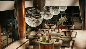 A lobby with tufted sofas, a wooden barrel planter, and a large chandelier. - Grand Vaves Otel (Trabzon)