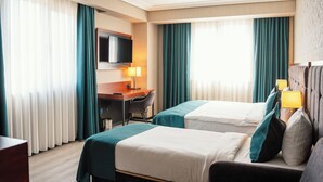 A hotel room with two beds, a desk, a TV, and a chair. - Grand Vaves Otel (Trabzon)