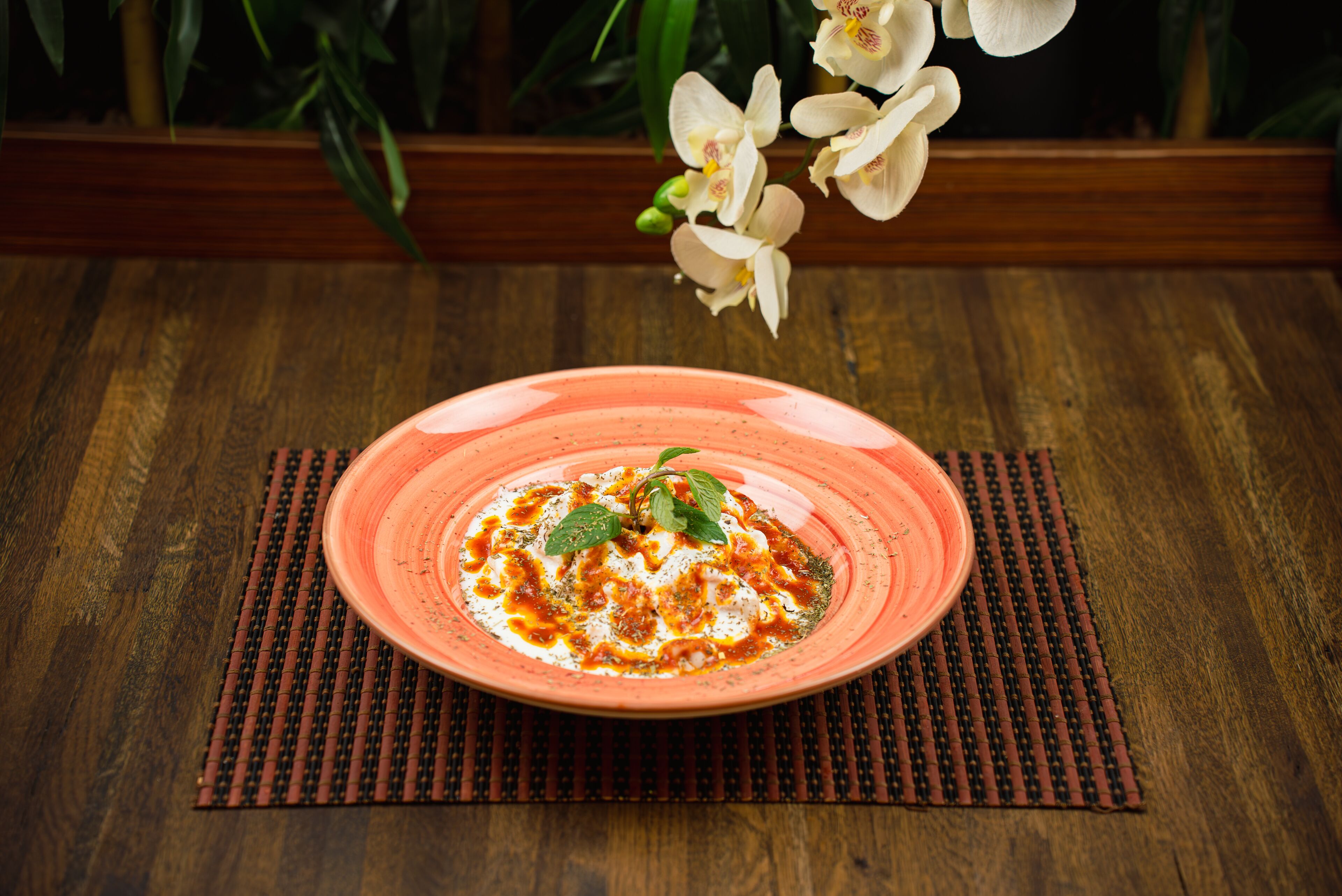 A plate of food on a wooden table with a placemat underneath.
