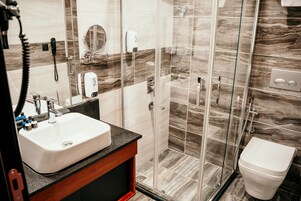 A bathroom with a white sink, mirror, and toilet, and a glass-enclosed shower area.