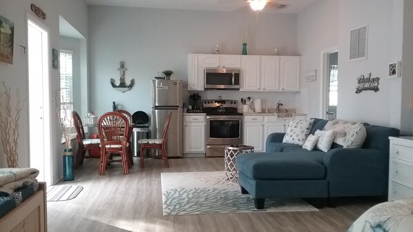 A compact living space with a kitchenette, a dining area, and a seating area with a sofa.