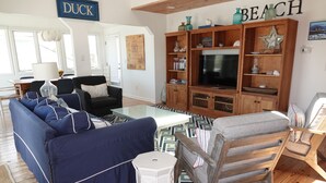 Una sala de estar con un sofá azul, un mueble de entretenimiento de madera y un televisor.