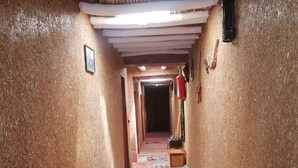 A hallway with a checkered carpet, wooden ceiling beams, and a fire extinguisher on the wall. - Gite Auberge Tigmmi N Tamazirte (Ijjoukak)