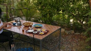 A table set outdoors with various dishes and a teapot. - Gite Auberge Tigmmi N Tamazirte (Ijjoukak)