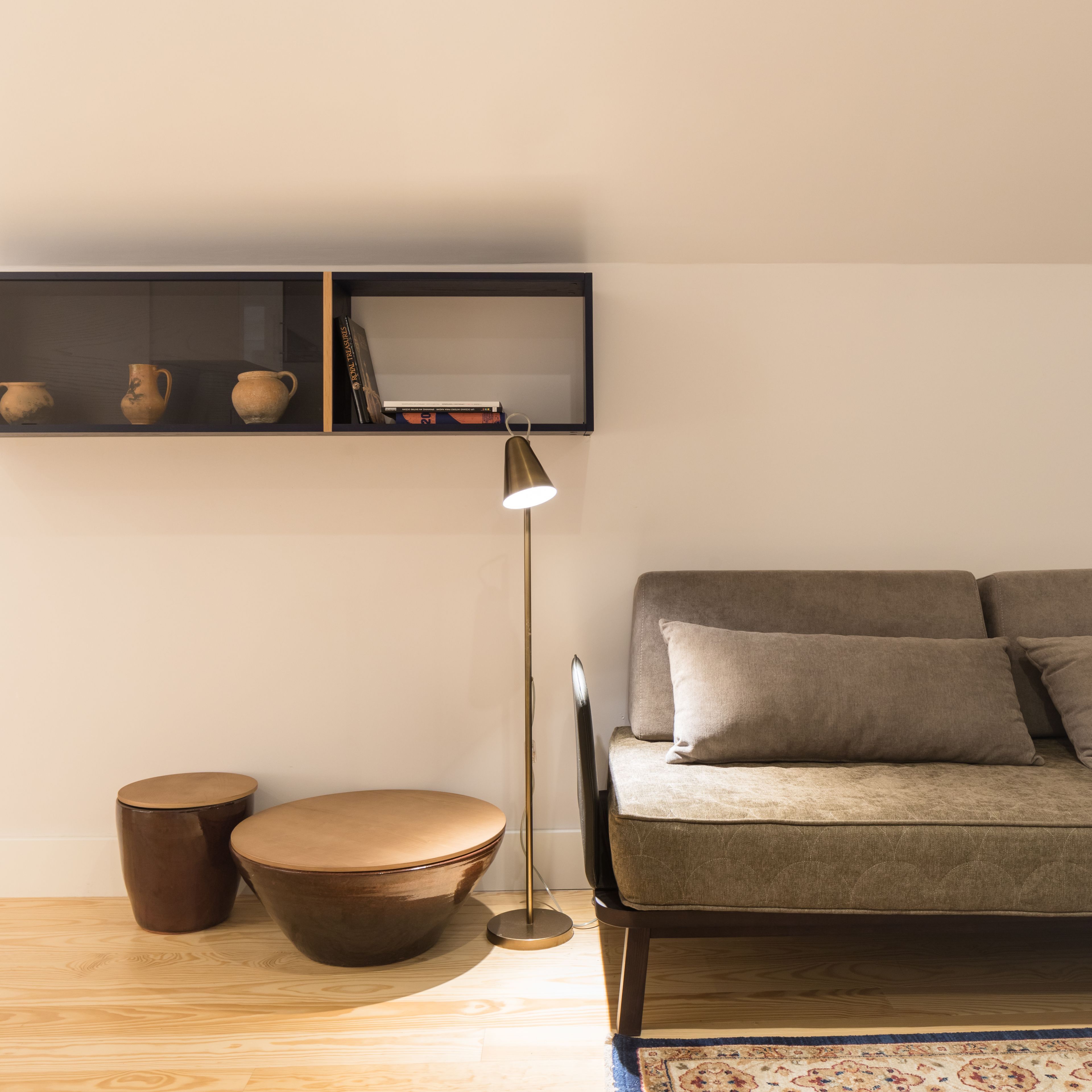 Un salon moderne avec un canapé, une lampe sur pied et une étagère ornée d’objets décoratifs.