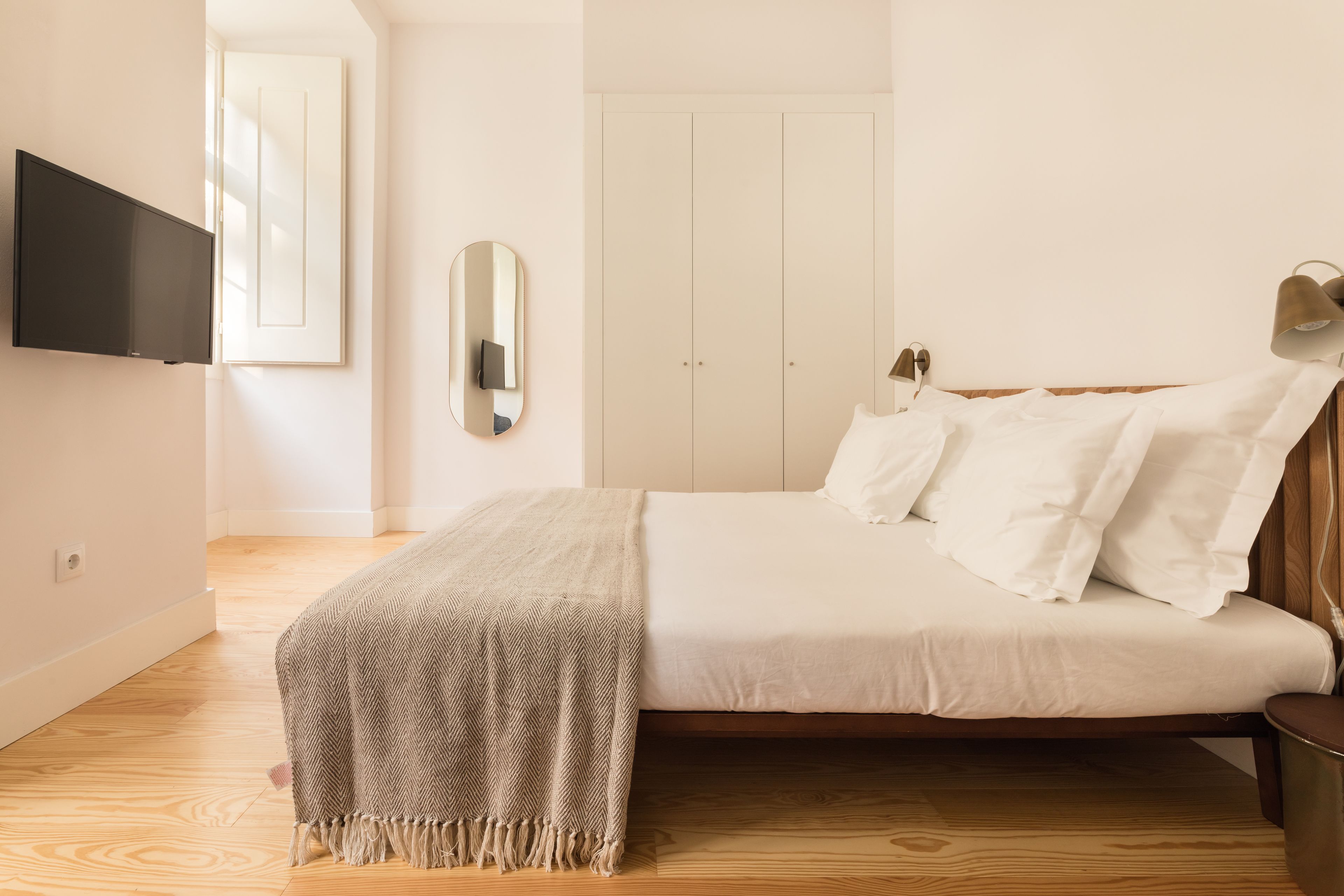 A bedroom with a bed, a TV mounted on the wall, and a door.