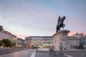 Eine Statue auf einem Platz, im Hintergrund Gebäude.