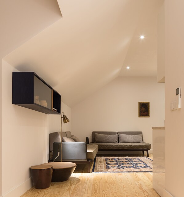 A modern, well-lit living room with a sofa, a small table, and a lamp. - The Visionaire Apartments (Lisbon)