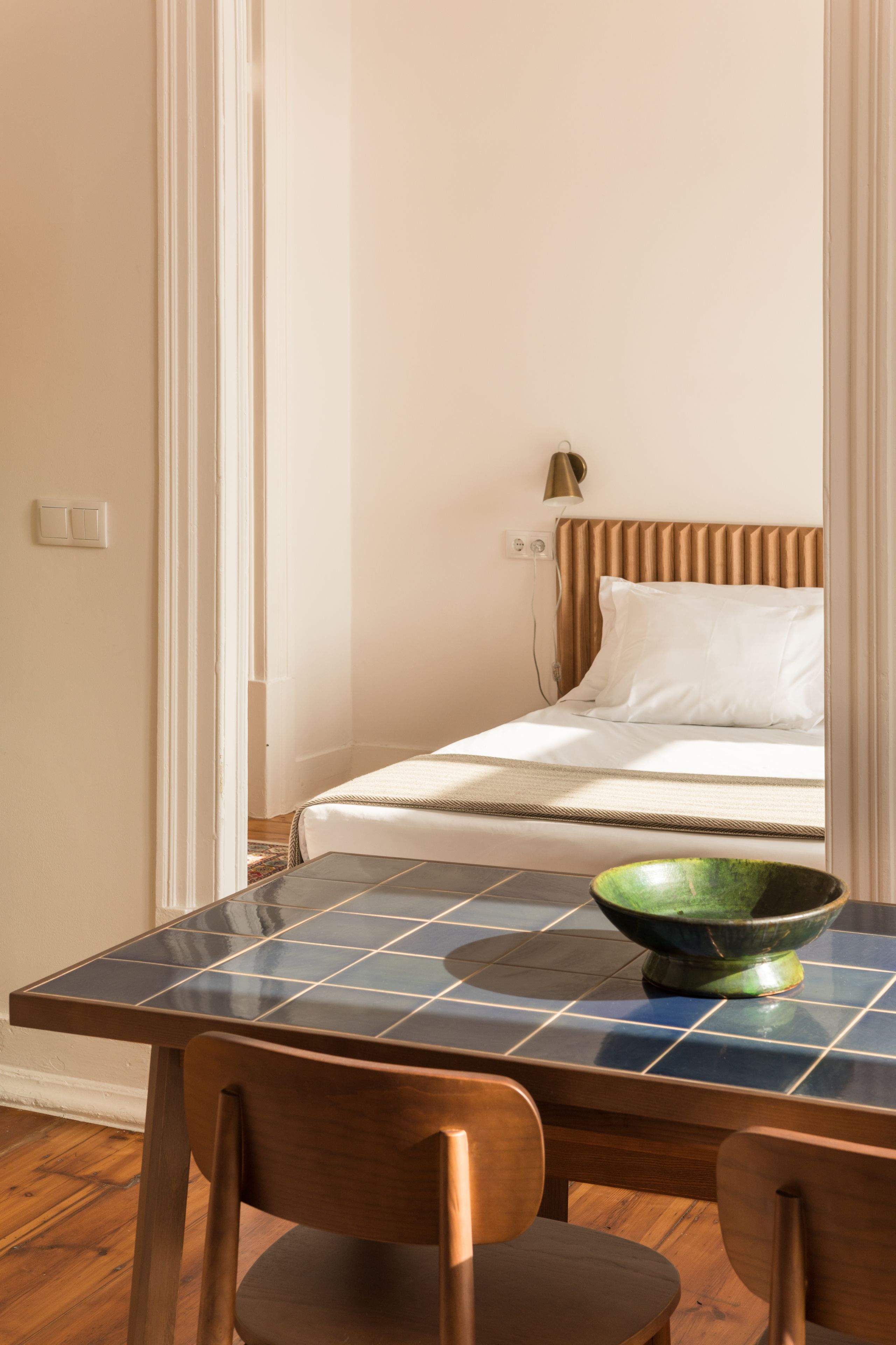 A bedroom with a bed, a bedside table with a bowl, and a chair.