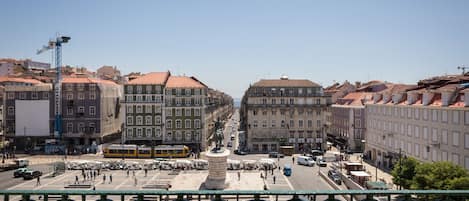 A city street with buildings, a statue, and a tram.