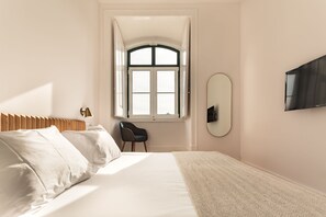 Ein Schlafzimmer mit Bett, Stuhl, Fenster und Fernseher.