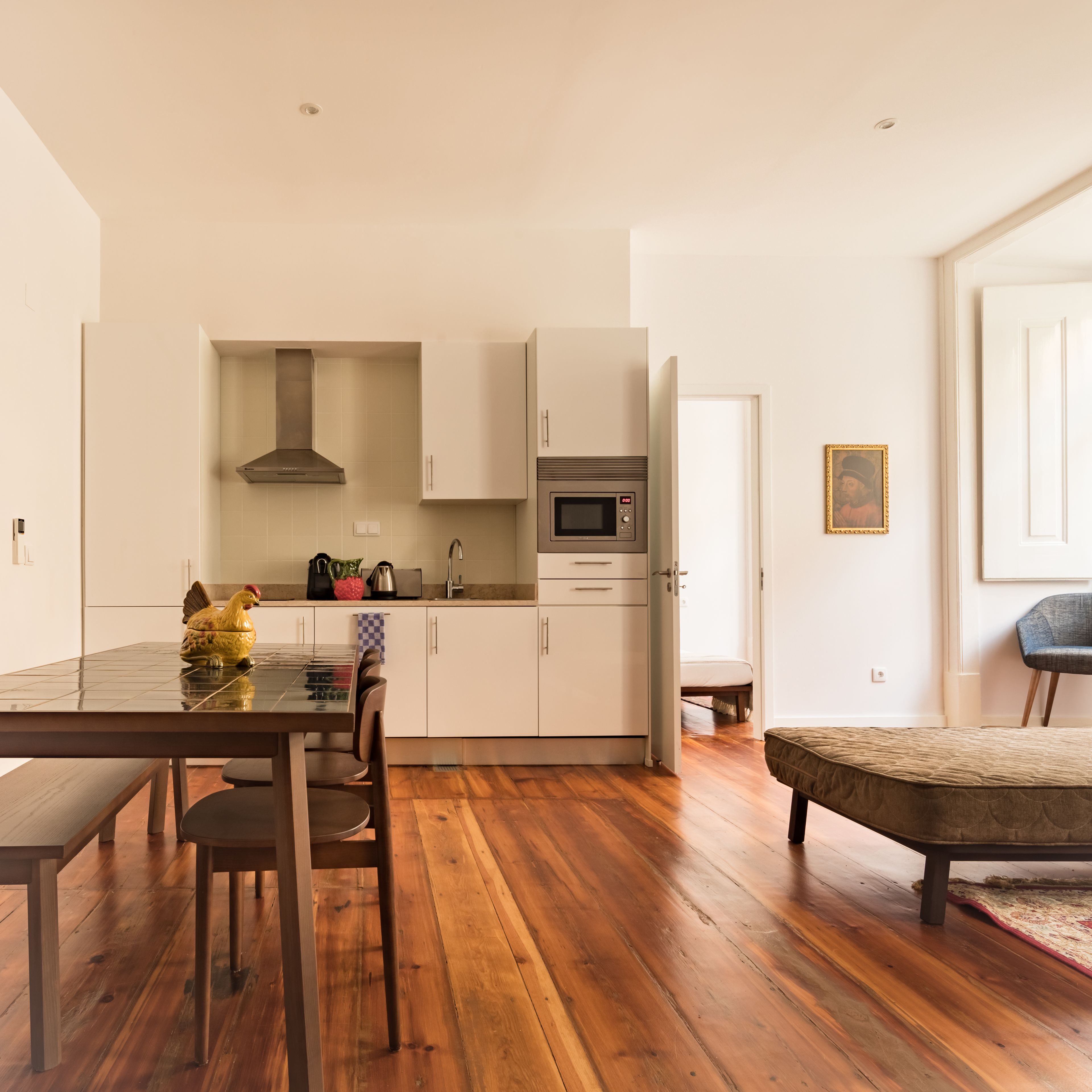 A modern kitchen with white cabinets, a microwave, and a stainless steel range hood.