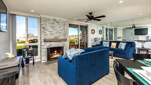 A spacious living room with a fireplace, a blue sofa, and a dining area.