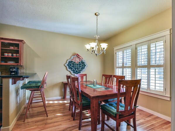 A dining room with a wooden table, chairs, and a chandelier.