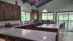 Cozinha com bancadas de granito, armários de madeira e uma ilha grande com banquetas.