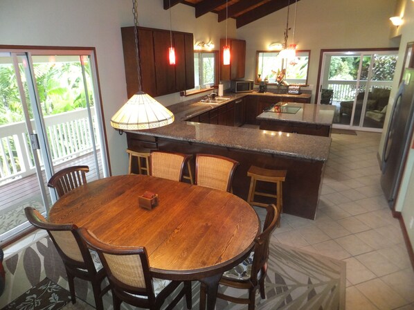 A spacious kitchen with a large island, wooden dining table, and chairs.