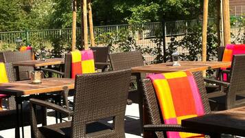 An outdoor seating area with wicker furniture and colorful blankets.