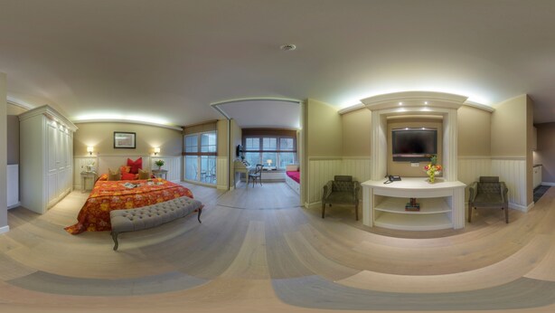 A spacious bedroom with a large bed, a vanity with a mirror, and a television. - Hotel Zur Traube (Perl)