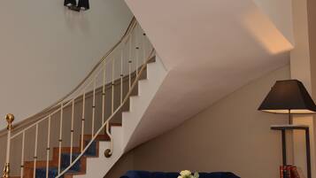 A staircase with a curved design, a blue sofa, a small table with a vase, and a lamp on a side table.