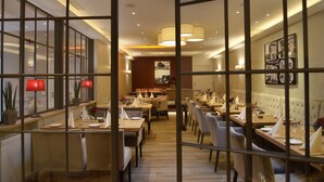 A restaurant with multiple dining tables, chairs, and red lamps. - Hotel Zur Traube (Perl)