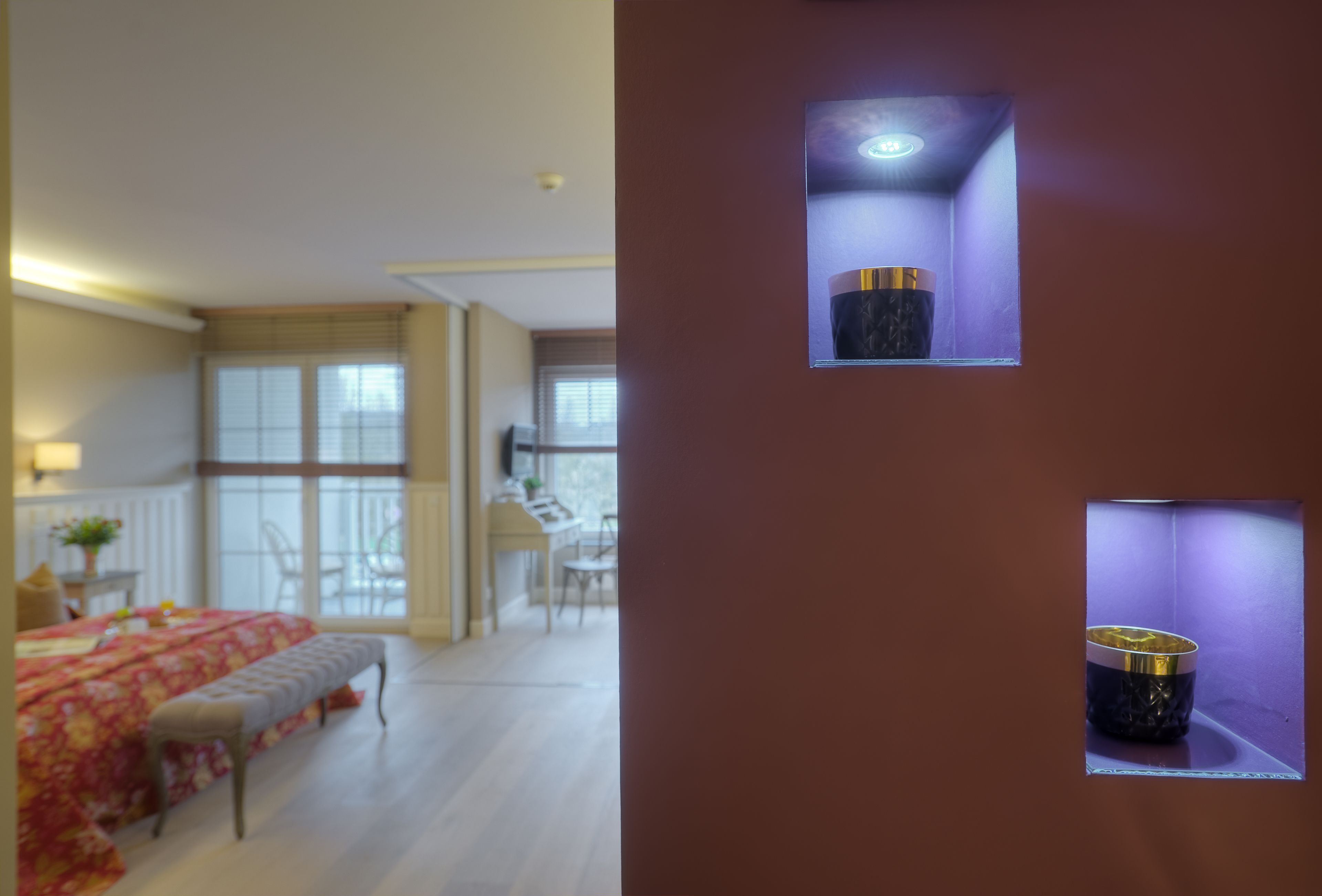 Une chambre avec un grand lit, un banc et une fenêtre donnant sur un coin repas.