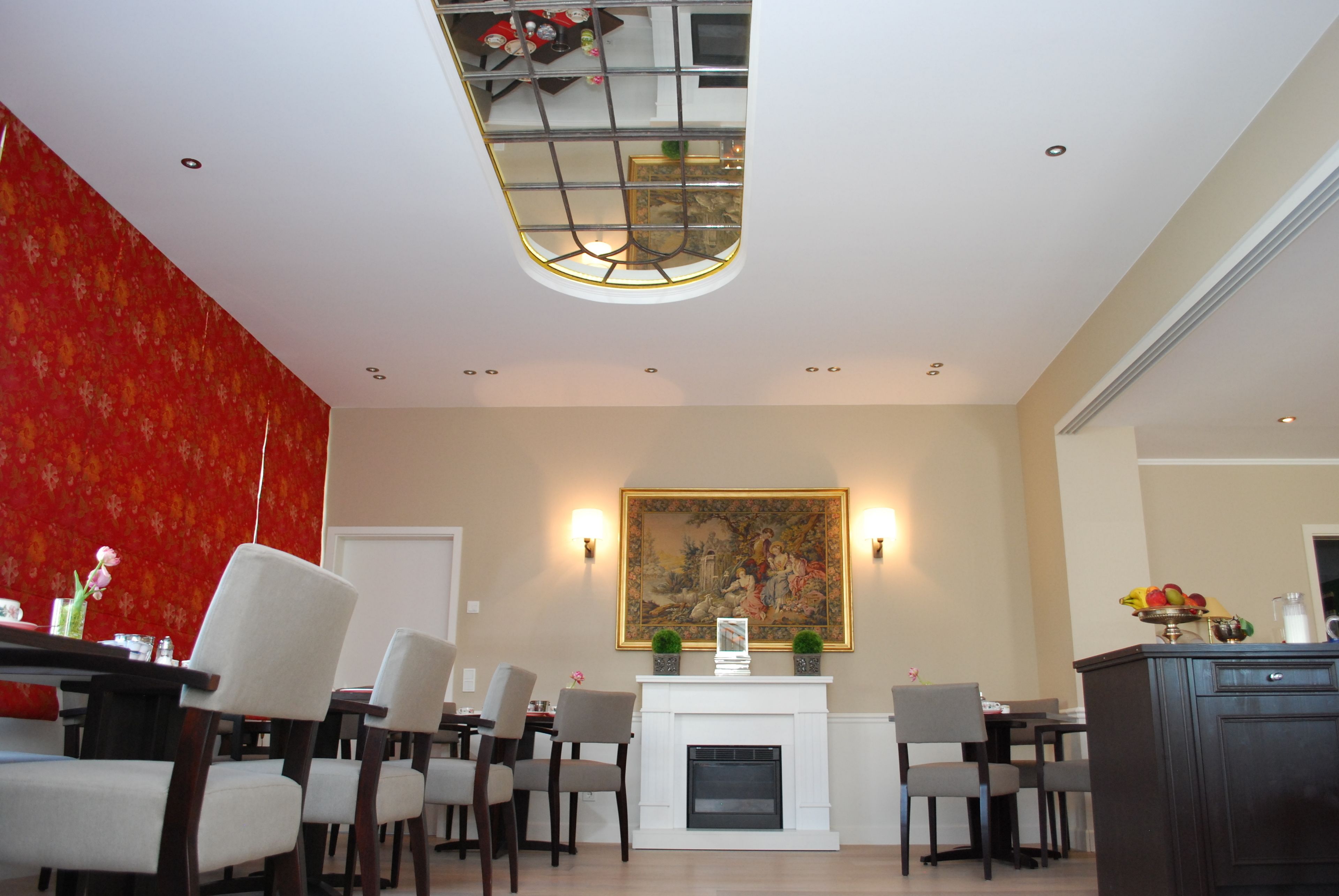 Un comedor con chimenea blanca, un cuadro grande encima y varias sillas alrededor de una mesa.