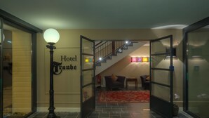 A hotel lobby with a staircase, a reception desk, and a large wall sign. - Hotel Zur Traube (Perl)
