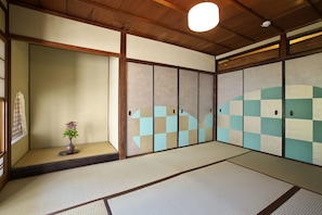 A traditional Japanese room with tatami flooring, sliding doors, and a small vase with flowers.