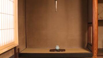 A traditional Japanese room with tatami flooring, a shoji screen, and a small water feature.
