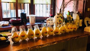 A bar area with a wooden counter, plastic-wrapped food items, and various bottles. - Gallery Nozawa Inn (Kyoto)
