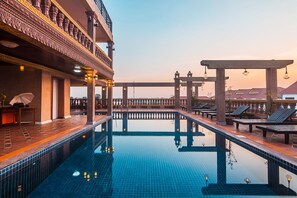 A rooftop pool with a tiled floor, lounge chairs, and a bar area with a view of the cityscape. - Hello Cambodia Boutique (Siem Reap)
