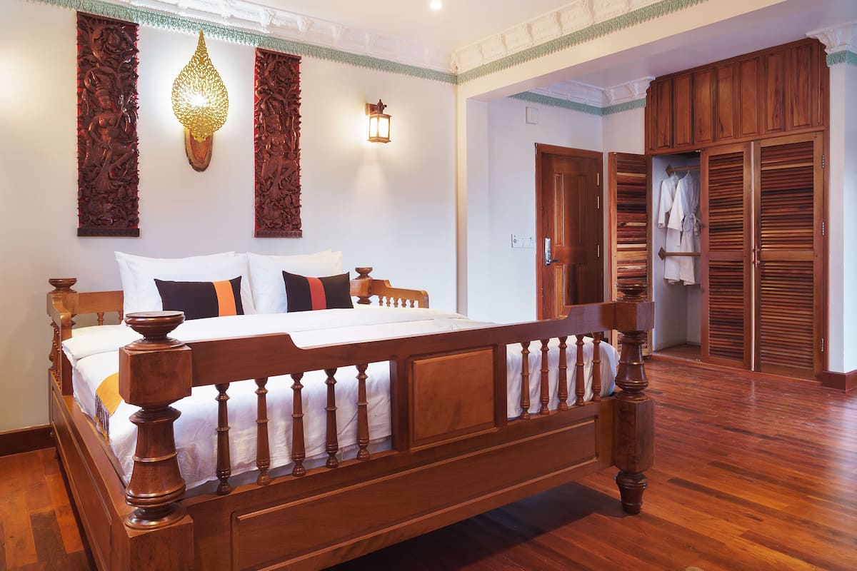 Quarto com cama de madeira, guarda-roupa e luminária suspensa.