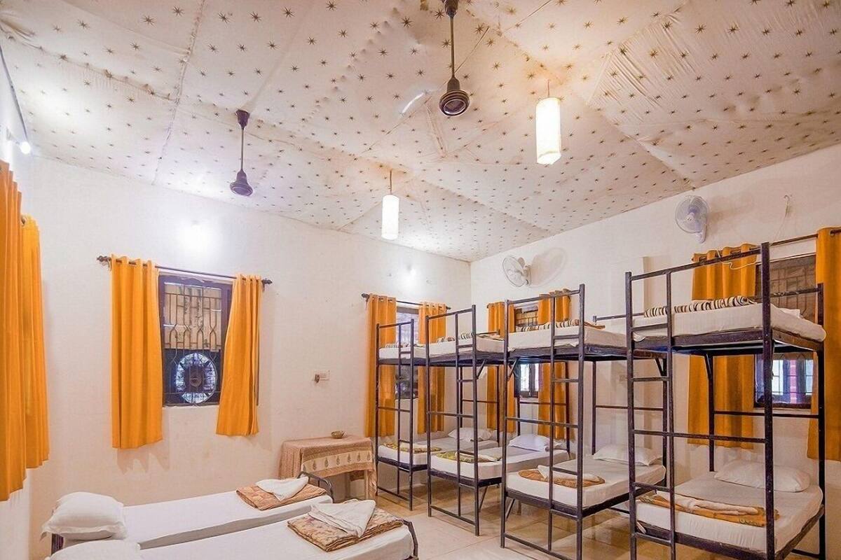 Un dormitorio con literas, una mesita pequeña y un ventanal con cortinas.