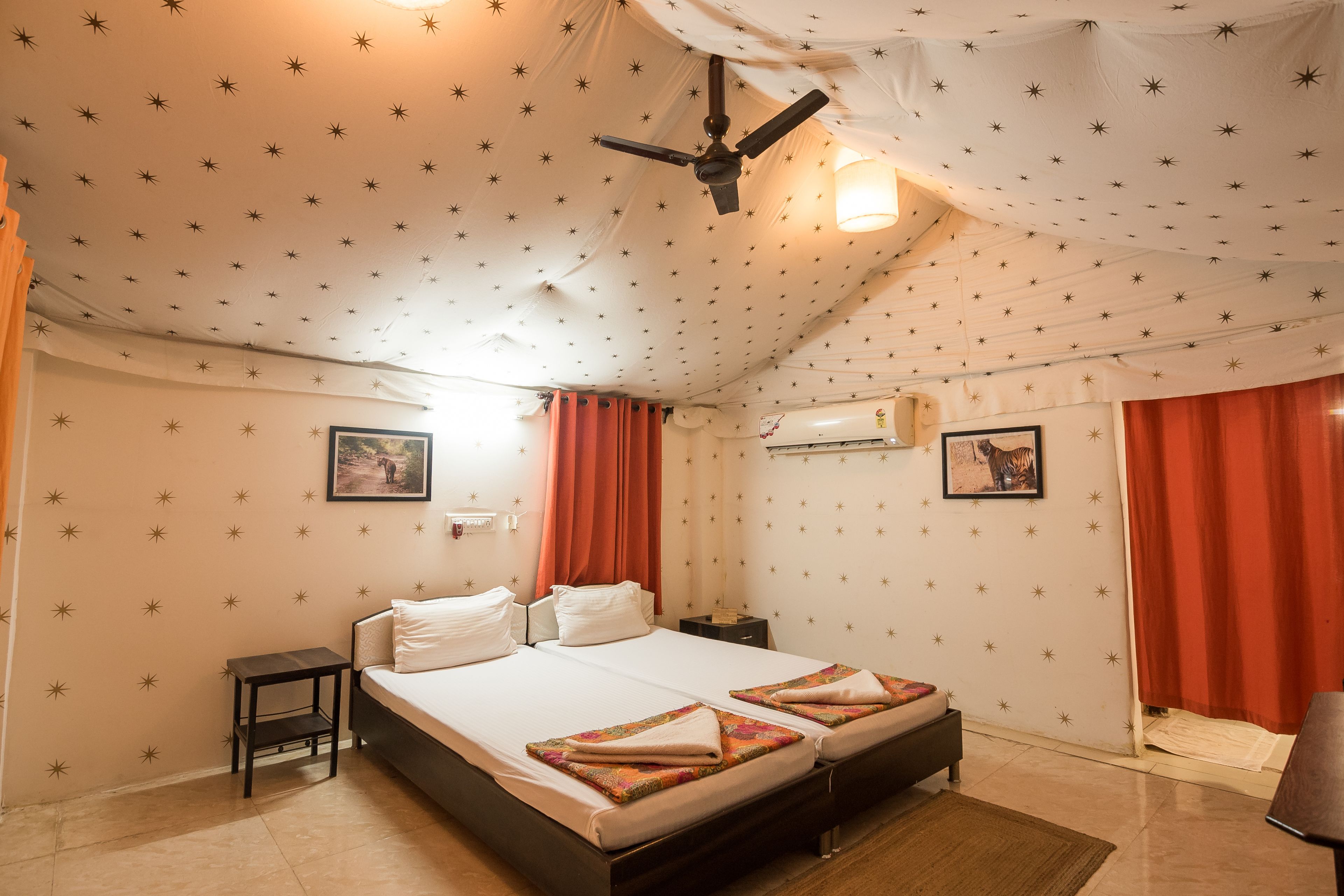 Une chambre comprenant un lit, une table de chevet, un ventilateur de plafond et un climatiseur fixé au mur.