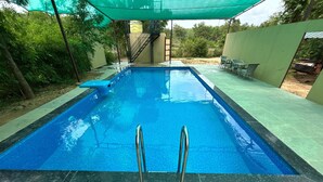 Una piscina rectangular con agua azul cristalina, rodeada por una solana con baldosas.