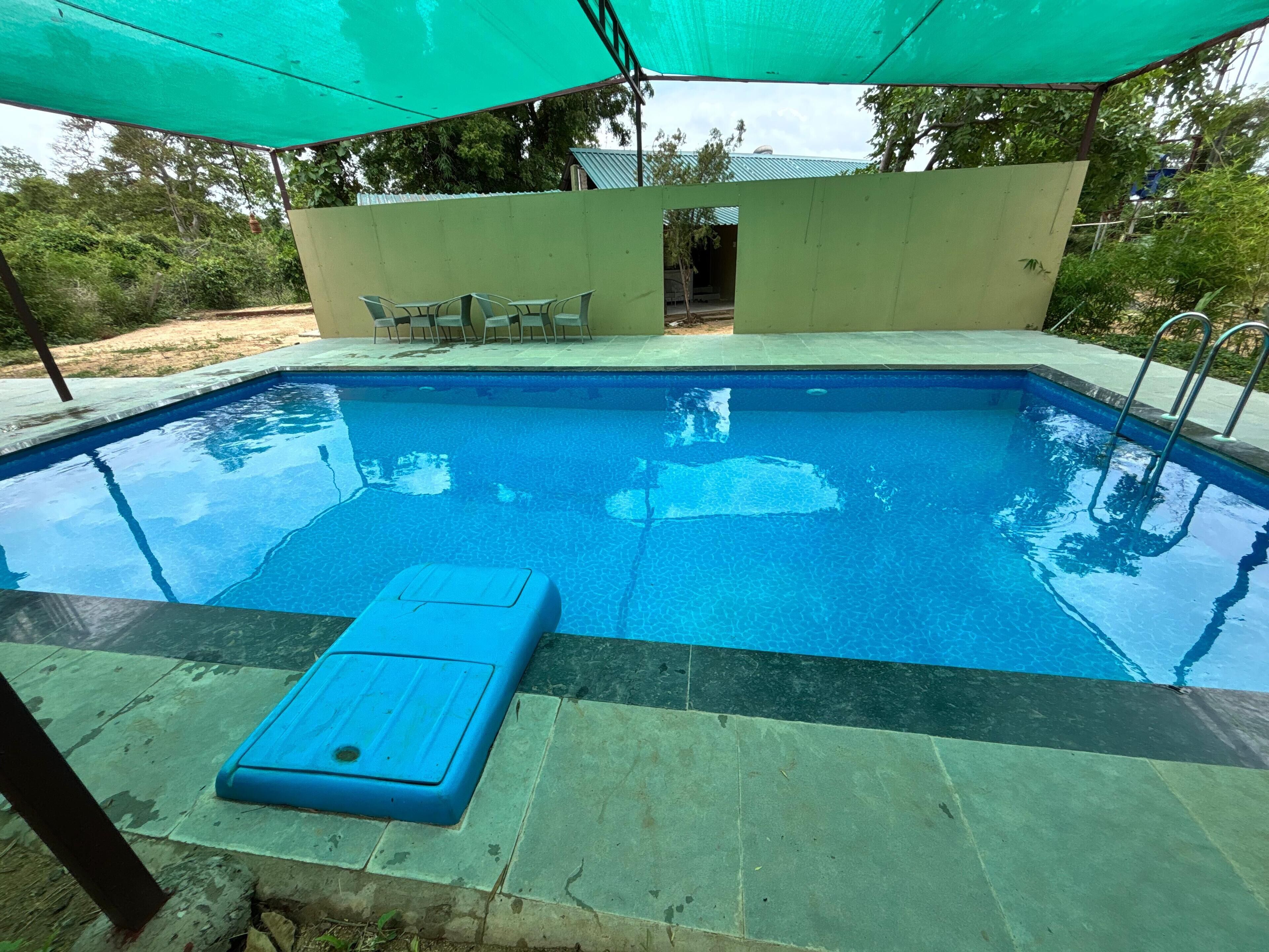 A rectangular swimming pool with a blue water surface, surrounded by a tiled deck.