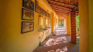 Un pasillo con piso de baldosas, una columna de ladrillo y cuadros en la pared.