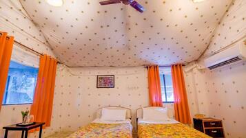 Ein Zimmer mit zwei Betten, einem Deckenventilator und einem fenster mit Vorhängen.