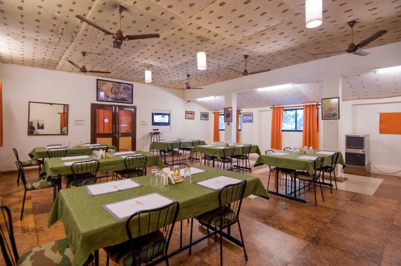 Ein Konferenzraum mit mehreren Tischen, Stühlen, Deckenventilatoren und einem Fernsehbildschirm.