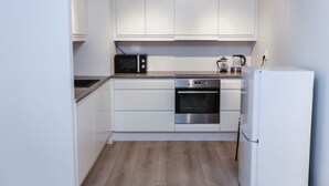 Una cocina con armarios blancos, microondas, horno y refrigerador.