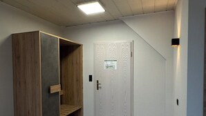 Una habitación con una cama, un armario de madera, una puerta con un letrero y una lámpara.