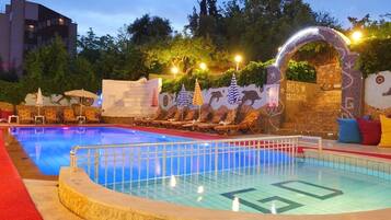 Alberca al aire libre, sombrillas en la alberca y camastros