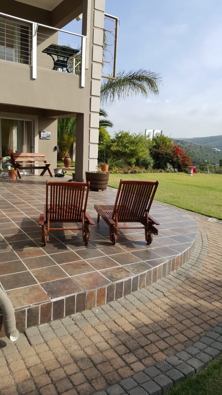 A patio area with two wooden chairs, a table, and a potted plant.