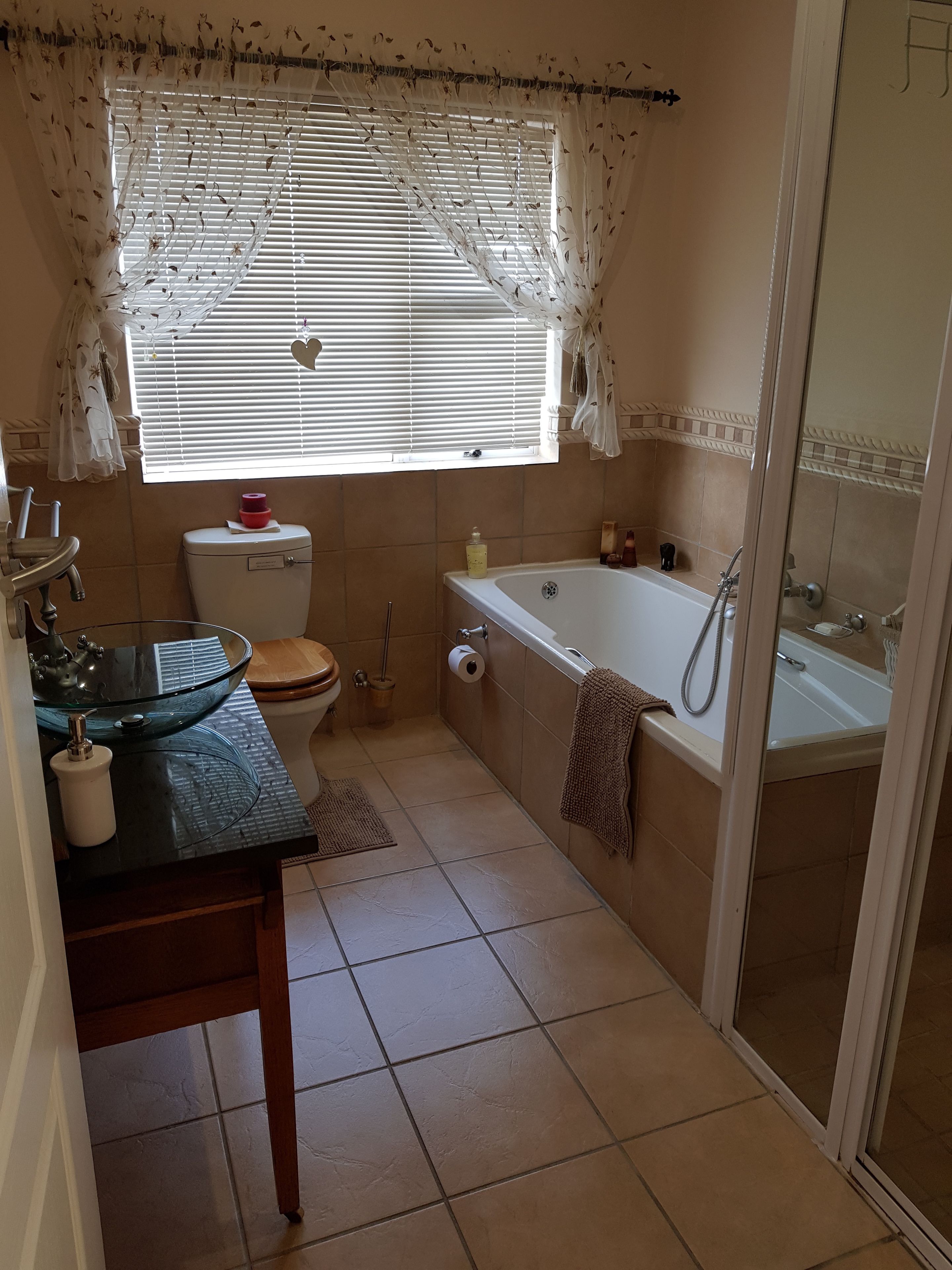 Et badeværelse med vask, toilet, badekar og brusebad.