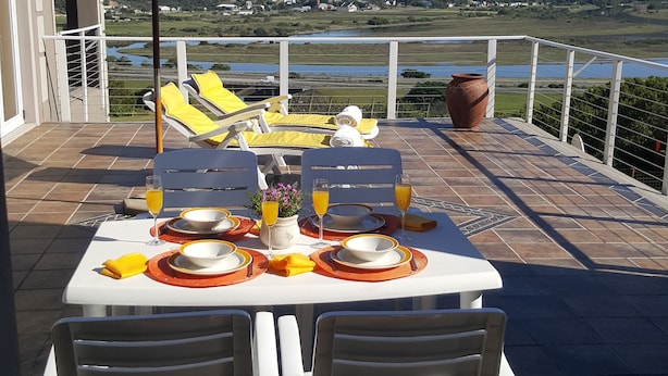 Una terraza con una mesa preparada para dos, con vistas a un paisaje pintoresco.