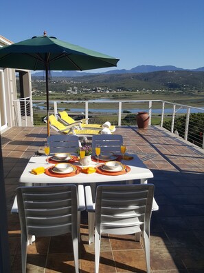 A terrace with a table set for two, overlooking a scenic landscape. - At 29 Columba (Great Brak River)