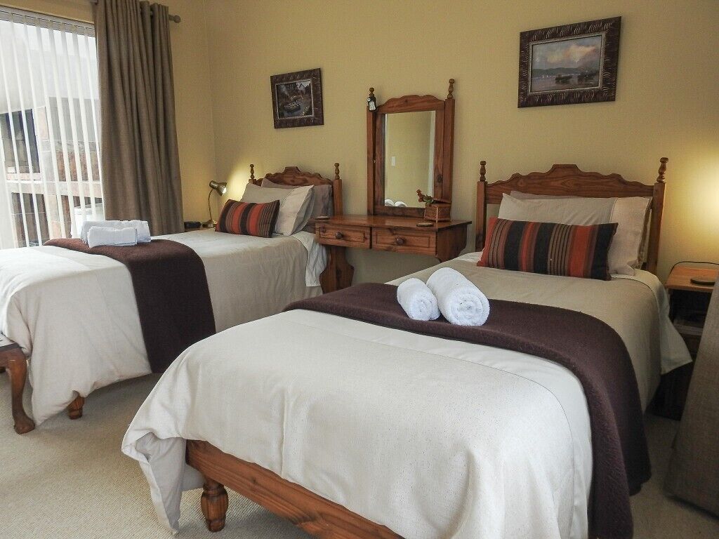 Habitación de hotel con dos camas, un aparador de madera, un espejo y dos cuadros en la pared.
