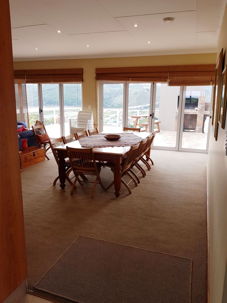A dining area with a large wooden table and chairs, a buffet setup, and a view through large glass doors.
