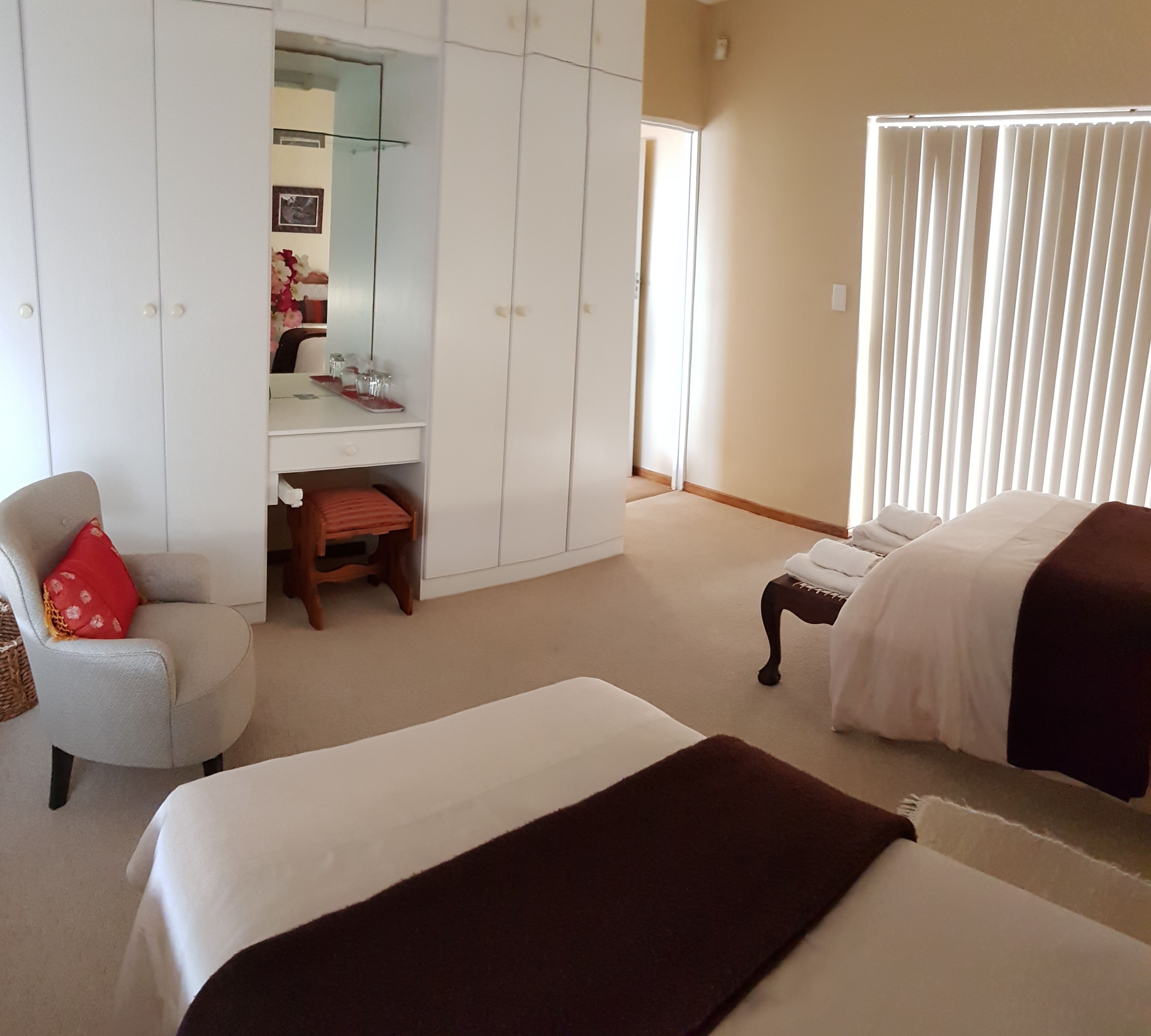 A bedroom with two beds, a desk, a chair, and a wardrobe.